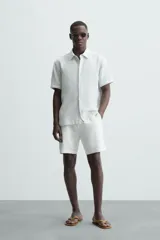 Bermuda azul marino de corte regular fit, confeccionada en tejido de algodón y lino. Cuenta con bolsillos frontales y traseros, cierre frontal con cremallera y botón.