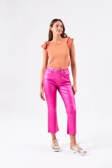 Top color salmón metalizado, de algodón peinado, con cuello redondo y mangas cortas con volados con borde fucsia.