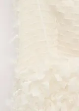 Blusa blanca sin mangas, con diseño asimétrico y textura de flecos tridimensionales en toda la superficie.