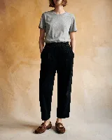 Pantalón de pana negro con cintura elástica, corte holgado y largo al tobillo. Presenta bolsillos delanteros y un detalle de costura en forma de corazón en el bolsillo trasero.