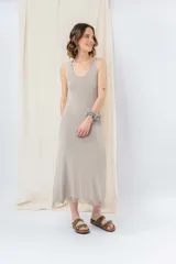 Vestido midi de tejido tipo seda con caída fluida, escote redondo y sin mangas. Presenta un diseño minimalista con detalle de flecos en el ruedo.