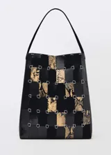 Bolso tipo shopper de diseño patchwork, confeccionado mediante tiras entrelazadas de cuero negro liso y cuero con estampado de serpiente, unidas por anillas metálicas plateadas. Cuenta con un asa de hombro fija y cierre magnético.