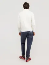 Sweater de punto acanalado en color azul marino, con cuello alto y cierre frontal parcial. Presenta mangas largas con puños acanalados y un pequeño logo bordado en rojo en el pecho.