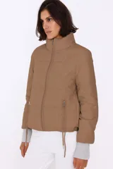 Campera puffer color crema con relleno de poliéster, cierre frontal y bolsillos laterales con cierre.