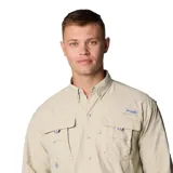 Camisa de manga larga Columbia modelo Bahama II, color beige. Confeccionada en tejido de secado rápido con protección solar UPF 50. Presenta cuello con botones, dos bolsillos frontales con solapa, rejillas de ventilación en la espalda y hombros, y pestañas para sujetar las mangas enrolladas.