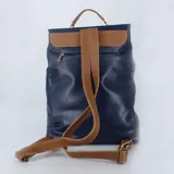 Mochila tipo portafolio de cuero azul con asa superior y correas ajustables color suela. Cierre frontal con hebilla y cierre trasero de seguridad.