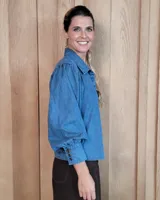 Camisa de jean azul con mangas largas abullonadas, puños ajustados y cuello clásico.