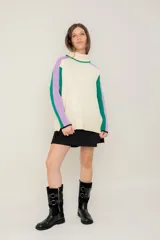 Buzo de punto con cuello alto, diseño de bloques de color en crema, verde y lila, con mangas largas y corte holgado.