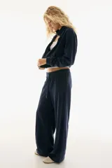 Pantalón tipo jogger de corte amplio confeccionado en tejido de velour suave. Presenta cintura elástica con cordón de ajuste y detalle de pliegue cosido vertical en el frente de cada pierna.