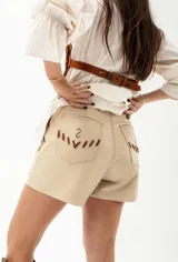 Short de cuero color beige con detalles de costuras en marrón.