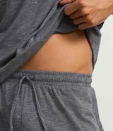 Conjunto de pijama para hombre, compuesto por una remera de manga corta y cuello redondo, y un short con cintura elástica y cordón de ajuste. El tejido es malla flamê con efecto mezcla en tonos de gris.
