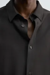 Camisa de corte relajado, color azul marino, con cuello solapa, manga larga con puños abotonados y cierre frontal de botones.
