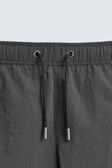 Bañador de hombre de largo medio, color celeste claro con rayas blancas horizontales. Presenta cintura elástica ajustable con cordón, bolsillos frontales y bolsillos traseros de plastrón. Incluye forro interior.