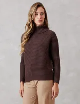 Buzo de tejido acanalado color blanco, con cuello alto y diseño de patrón en V en el frente. Presenta un corte holgado con mangas integradas sin costura de sisa.