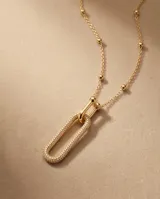 Collar de bronce con baño de oro, diseño de cadena con pequeñas cuentas esféricas y un dije colgante en forma de eslabón alargado completamente pavimentado con circonias.