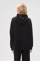 Canguro negro holgado con capucha y cordones ajustables, mangas largas y bolsillos laterales.