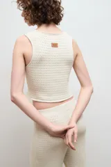 Chaleco negro de punto con escote en V y cierre frontal con dos ganchos metálicos.