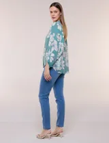 Blusa holgada de gasa texturizada color blanco con estampado de lunares negros, escote en V con botones frontales, mangas 3/4 abullonadas y puños elásticos.