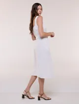 Vestido midi abotonado verde melange, con escote recto, tirantes anchos y falda de calce recto con vuelo sutil. Tiene abotonadura frontal completa con botones estilo carey, cinto textil con hebilla para ajustar la cintura y bolsillos laterales.