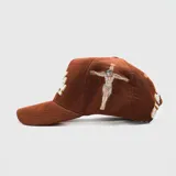 Gorra tipo trucker de pana color marrón, con bordado frontal en relieve y detalle lateral bordado del Sagrado Corazón de Jesús.