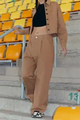 Pantalón camel de gabardina elastizada, corte sastrero, tiro bajo, con bolsillos delanteros, botón metálico y tajo en el lateral interno.