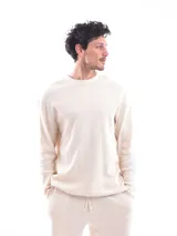 Buzo de punto color crema, de corte holgado y manga larga.