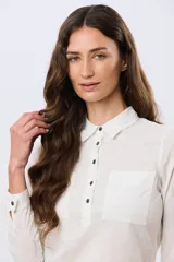 Camisa de lino lisa color celeste, de manga larga con puños abotonados y trabilla para arremangar. Cuenta con cuello clásico, cierre frontal con botones y bolsillos plaqué en el pecho.