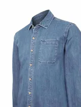 Camisa de manga larga de denim azul claro con efecto lavado, cuello camisero, botones frontales y un bolsillo de parche en el pecho izquierdo.