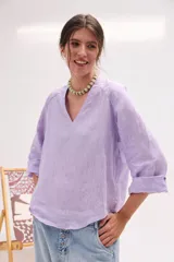 Blusa de lino color lila, de corte relajado y mangas largas amplias, con escote en V y ruedo curvo.