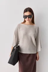 Sweater de punto liviano negro, con escote bote y mangas amplias de largo tres cuartos que aportan una silueta relajada y fluida.