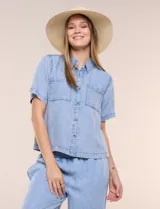Camisa de corte recto y calce fluido color celeste, confeccionada en lyocell con efecto lavado, cuello camisero tradicional, botones a tono, dos bolsillos aplicados en el pecho y mangas cortas.