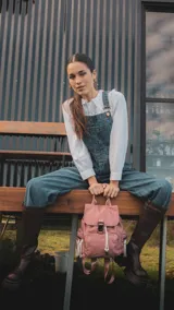 Mochila de nylon color rojo, con tapa frontal, broche metálico y cierre tipo marinero. Cuenta con bolsillo frontal con cierre metálico, bolsillos laterales, asas de mano y correas regulables para la espalda.