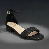Sandalias de tacón bajo cuadrado, color negro con acabado brillante y glitter. Presentan una tira frontal ancha y una tira ajustable al tobillo con hebilla metálica dorada.