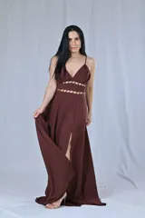 Vestido largo color beige, con breteles finos y escote en V. Presenta detalles de argollas doradas en la cintura y en el busto.