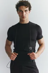 Remera deportiva de compresión color negro, con cuello redondo, mangas raglán cortas y costuras planas antifricción.