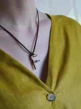 Collar de tiento de cuero marrón con dije en forma de letra con acabado rústico en bronce.