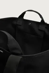 Bolso shopper negro fabricado en tejido técnico, con compartimento principal con cierre de botón a presión, múltiples bolsillos exteriores frontales, doble asa de mano y asas largas de hombro.