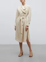 Vestido midi de lino y viscosa color beige, con cuello chal asimétrico, cierre frontal con botones, manga larga con puños abotonados, lazo ajustable en la cintura y tajos laterales en el ruedo.