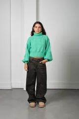 Polera de punto color verde menta, con cuello alto, mangas globo y diseño de trenzas en el frente.