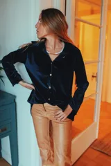 Camisa azul marino de terciopelo con cuello clásico, cierre frontal con botones dorados, mangas largas con puños abotonados y dos bolsillos de parche en el pecho.