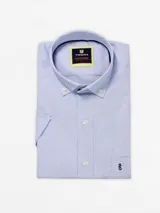 Camisa de hombre de manga corta, confeccionada en algodón con diseño a cuadros celestes y blancos. Tiene cuello abotonado, cierre con botones y bolsillo en el pecho con logo bordado.