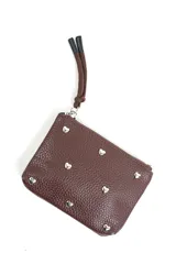Billetera pequeña color marrón de cuero sintético con textura granulada, detalle de tachas plateadas en forma de corazón y correa de mano con cierre superior.