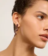 Aros colgantes medianos con forma de serpiente, esmaltados en color marrón y blanco con detalles dorados.