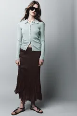 Chaqueta estilo polo de manga larga confeccionada en tejido de punto con hilo metalizado. Presenta cuello solapa y cierre frontal con botones.