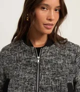 Campera bomber corta confeccionada en tweed con cuello alto, cierre frontal con cremallera, bolsillos y detalles en rib.