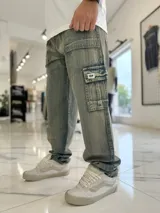 Pantalón cargo de jean azul claro, con bolsillos laterales tipo cargo en las piernas y bolsillos frontales aplicados, de corte ancho y holgado.