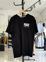 Remera oversize blanca de manga corta, con gran estampado negro en la espalda con la palabra 'Peace' y símbolos gráficos.