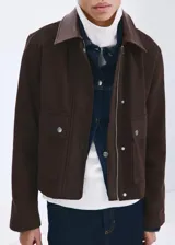Chaqueta de algodón estilo tejano de corte recto, color marrón, con cuello camisero de efecto piel en contraste, manga larga y dos bolsillos de parche con solapa y botón en el frente. Cuenta con cierre oculto de cremallera y botones.