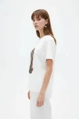 Remera blanca de manga corta y cuello redondo, confeccionada en algodón, con un diseño holgado y estampado frontal de estrella roja con textura y detalles de estrellas pequeñas.