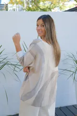 Sweater de punto con diseño de ondas en tonos beige y gris, de corte amplio, escote en V y mangas largas con puños vueltos.